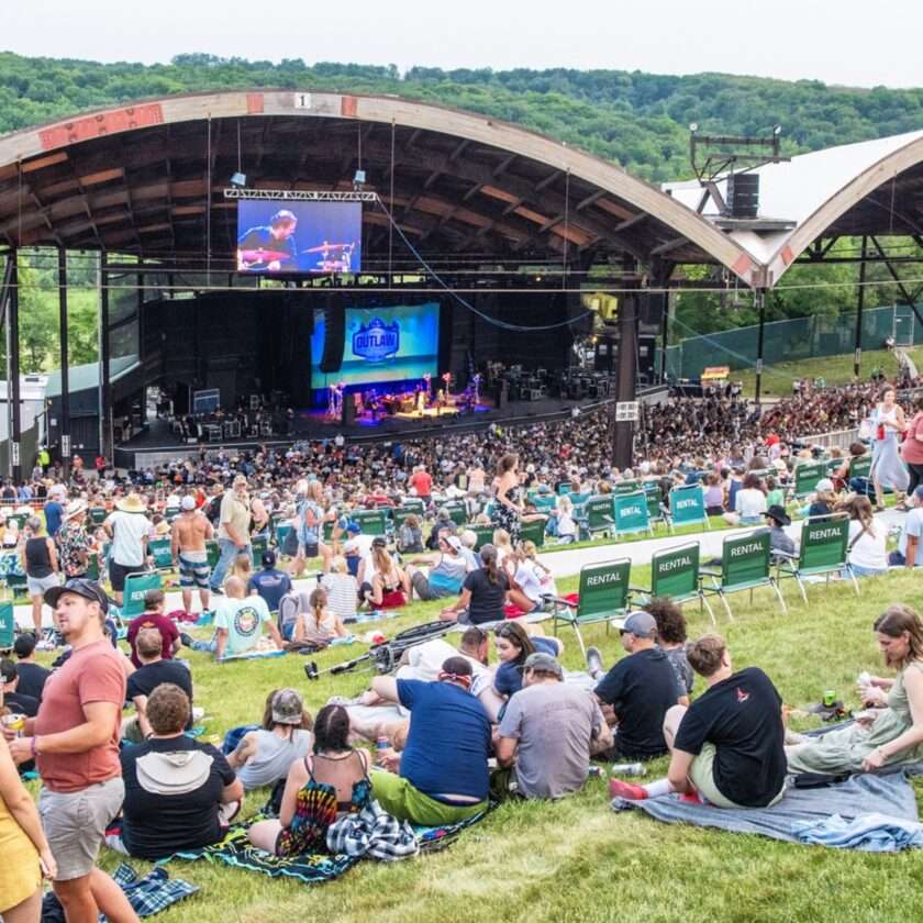 How The Outlaw Music Festival is Inspiring a New Generation of Acoustic Rebels Crowd on a hill in front of a stage